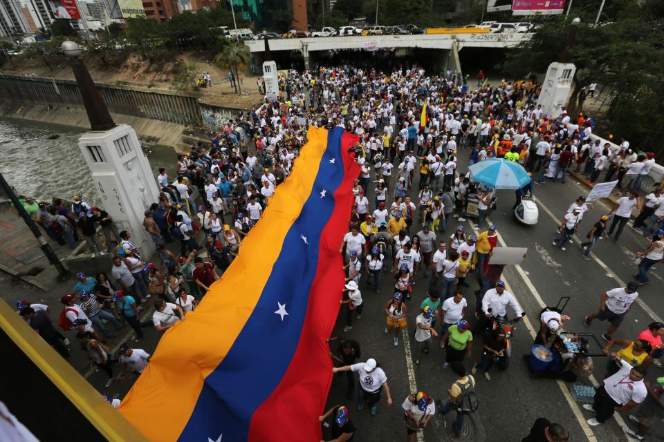 Demonstrators display a Venezuelan flag during a protest in Caracas, Venezuela, Sunday, March 2, 2014. Since mid-February, anti-government activists have been protesting high inflation, shortages of food stuffs and medicine, and violent crime in a nation with the world's largest proven oil reserves.(AP Photo/Fernando Llano)