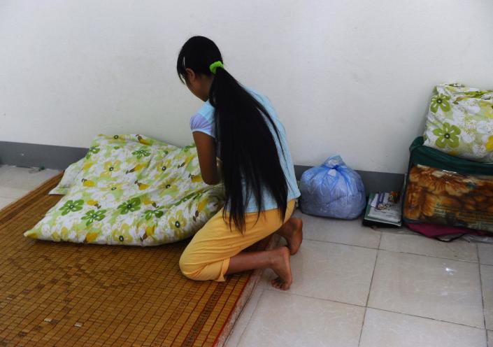 H'mong ethnic girl Kiab (whose name has been changed to protect her identity) makes her bed at a government-run centre for trafficked women in the northern city of Lao Cai, May 9, 2014 (AFP Photo/Hoang Dinh Nam)