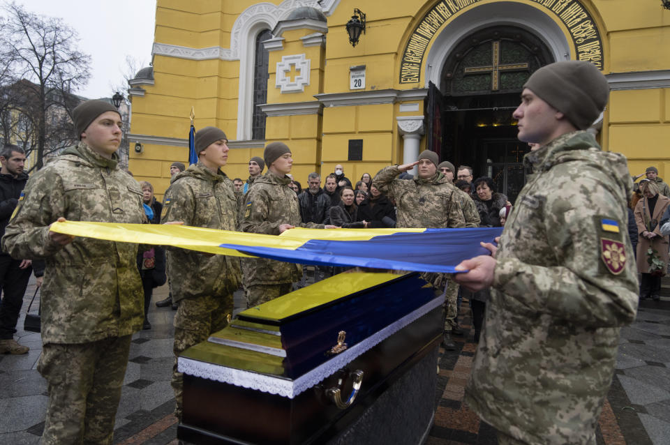 Ukrainian servicemen hold a flag over the coffin of their comrade during the funeral ceremony of Volodymyr Yezhov killed in a battlefield with Russian forces at St. Volodymyr Cathedral in Kyiv, Ukraine, Tuesday, Dec. 27, 2022. Yezhov was a game designer in the development of the game Cossacks 2. He was also one of the authors of the game S.T.A.L.K.E.R.: Clear Sky. Yezhov was also one of the most famous Ukrainian e-sportsmen — played StarCraft under the nickname Fresh. Since the Russian invasion, Volodymyr Yezhov went to the frontline and fought as part of the volunteer squadron. (AP Photo/Efrem Lukatsky)