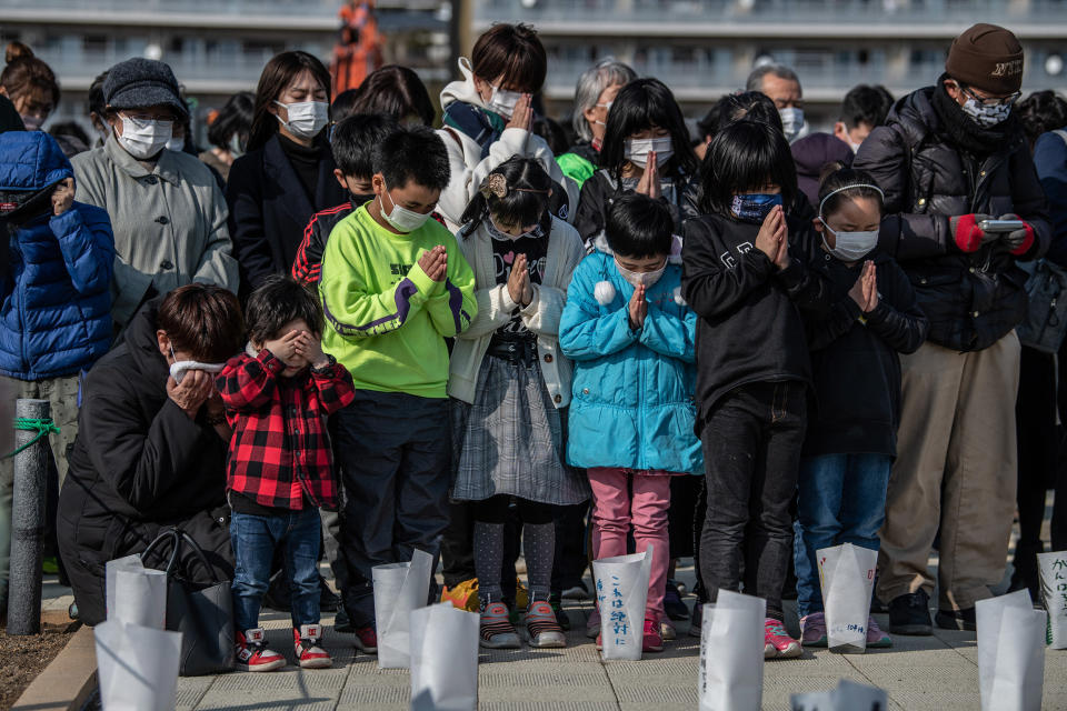 Image: A woman and child cover their eyes as others pray during a minute of silence to mark the 10th anniversary of the 2011 Tohoku earthquake and tsunami (Carl Court / Getty Images)