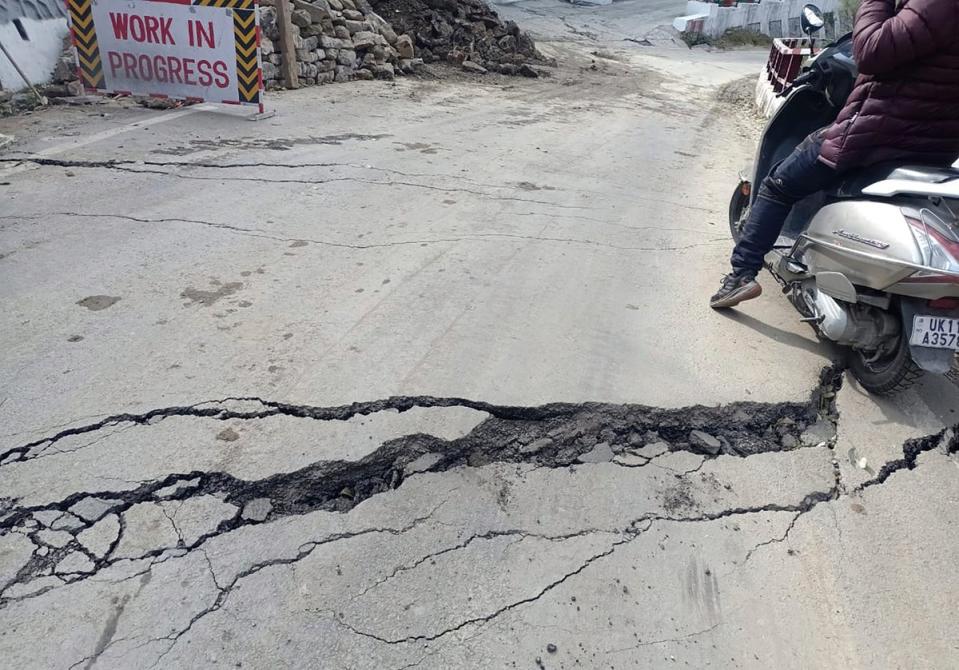 A motorist navigates his way through a crack on a road in Joshimath, India (AP)