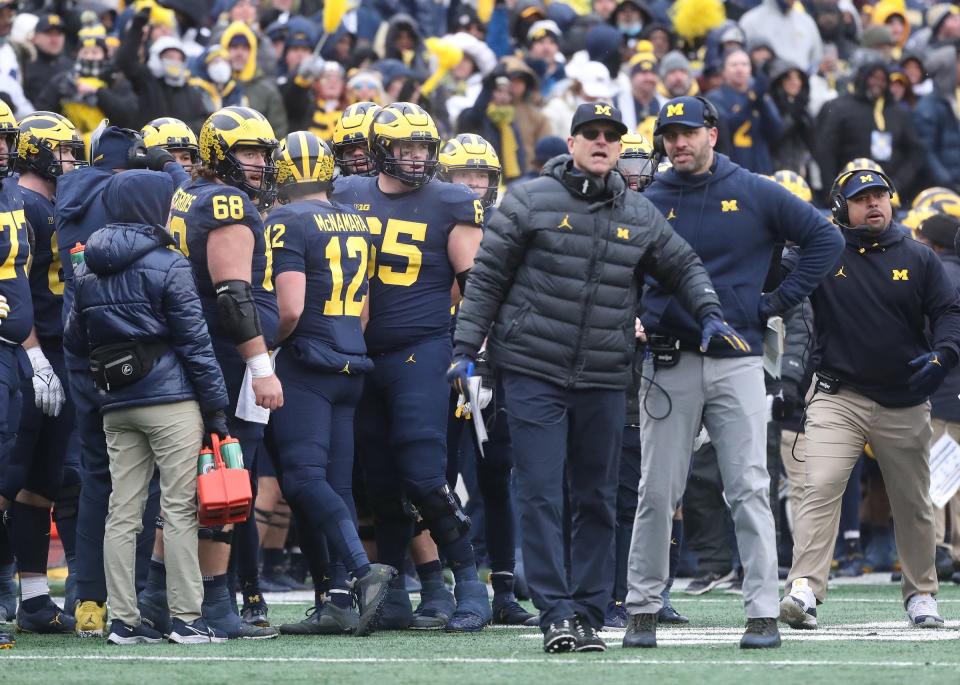 Michigan Wolverines head coach Jim Harbaugh, center, speaks with quarterbacks coach Matt Weiss, right, during action against the Ohio State Buckeyes on Saturday, Nov. 27, 2021 at Michigan Stadium.