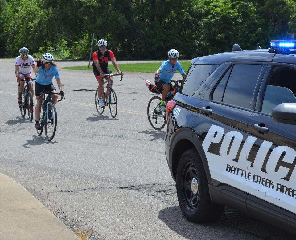 Battle Creek's Nicole Jaeger gets a police escort into town on Tuesday as she nears the end of her 2,000-plus mile 'Ride For Poppy' that has seen her ride her bike from Oregon to Michigan in an effort to raise money for cancer research in honor of her late father.