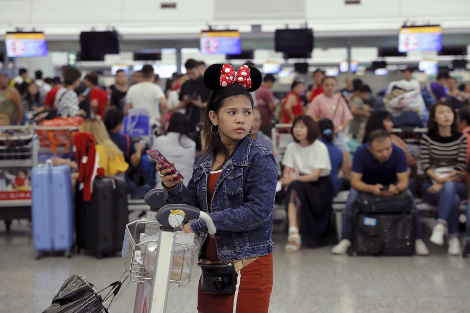 A woman wearing Minnie Mouse headgear looks on as stranded travelers gather near the closed check-in counters at the Airport in Hong Kong, Tuesday, Aug. 13, 2019. Protesters severely crippled operations at Hong Kong's international airport for a second day Tuesday, forcing authorities to cancel all remaining flights out of the city after demonstrators took over the terminals as part of their push for democratic reforms. (AP Photo/Kin Cheung)