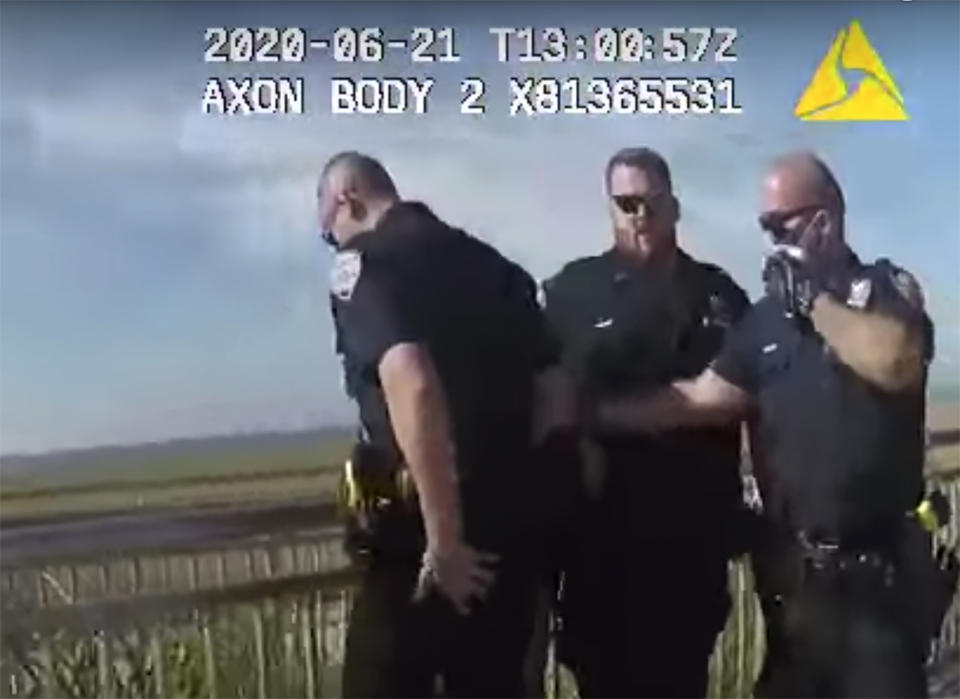 In this photo taken from police body cam video, New York Police officers, including officer David Afanador, right, arrest a man on a boardwalk in New York's Rockaway Beach on Sunday, June 21, 2020. Video showed Afanador with his arm wrapped around the man's neck for several seconds during the arrest. Afanador was arrested Thursday, June 25, on charges of strangulation and attempted strangulation over the incident. (New York Police Department via AP)