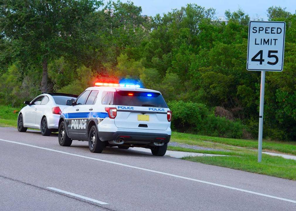 highway patrol pulling over driver next to speed limit sign