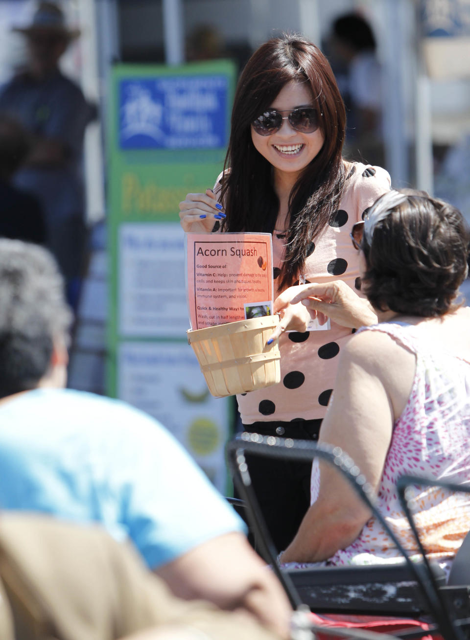 In this photo taken Wednesday, June 5, 2013, Helen Ma, a nutrition intern, center, explains the nutritional value of Acorn Squash to clients of the Sacramento Food Bank in Sacramento, Calif. The Sacramento Food Bank is one of the nations' first farm-to-fork food banks using local growers to provide healthier food to it's clients. Along with providing fresher food, the food bank provides nutritional and cooking information.(AP Photo/Rich Pedroncelli)