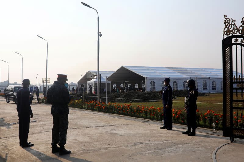 Security personnel guard the entrance of the makeshift tents where Rohingyas wait to board a ship to move to the Bhasan Char island, in Chattogram