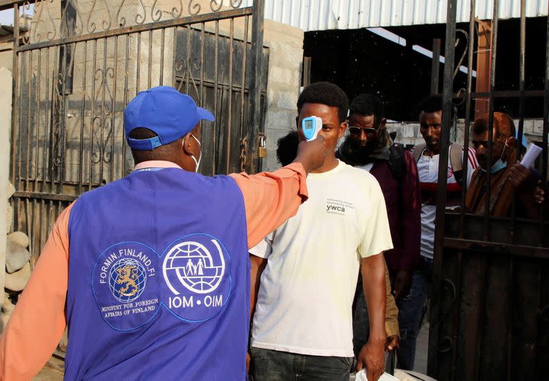 IOM staffer checks the temperature of Ethiopian migrants as they leave an IOM shelter before they were flown back to Ethiopia, in Aden