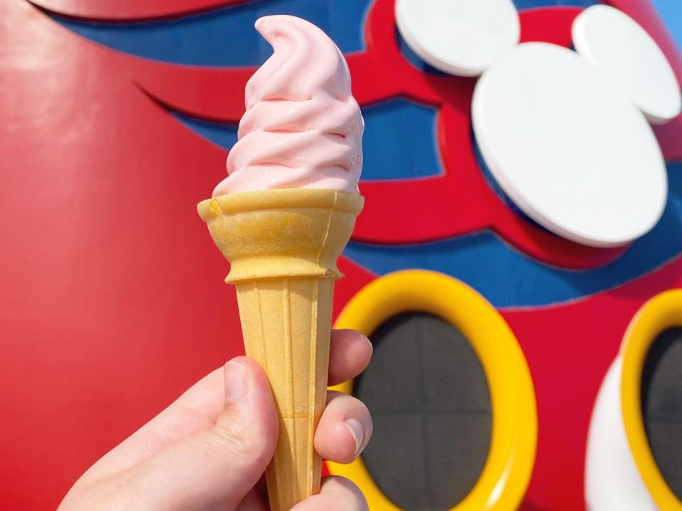 hand holding cone of soft serve on the deck of a disney cruise ship