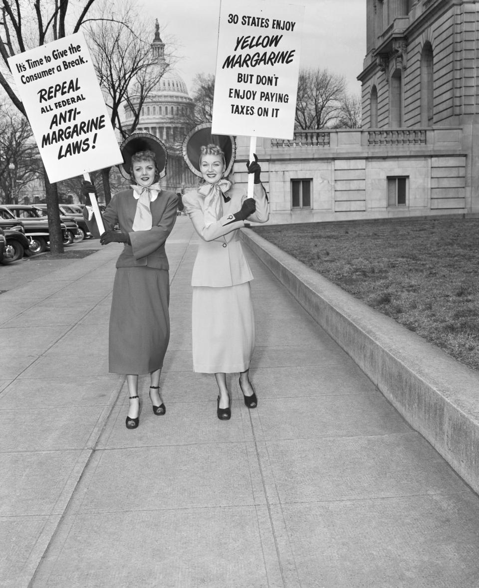 Two housewives in gay blue bonnets, Mrs. J.C. Alicoate (L) of Miami, and Mrs. Arthur Hebb, Jr. of Baltimore, add their bit towards the fight for repeal of the tax on oleomargarine. They parade with their signs near the Capitol in Washington, D.C. on March 3, 1949.