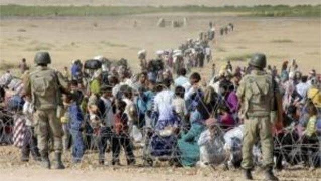 Turkish soldiers stand guard as Syrian Kurds wait behind the border fence to cross into Turkey near the southeastern town of Suruc in Sanliurfa province, September 19, 2014. Source: Reuters