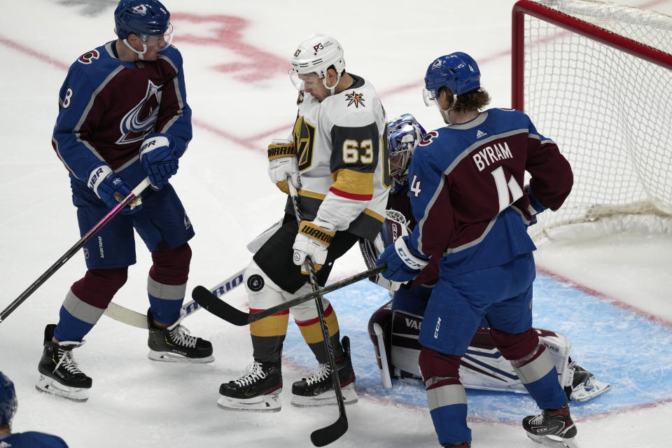 Vegas Golden Knights right wing Evgenii Dadonov (63) takes the puck off his knee as Colorado Avalanche defensemen Cale Makar, front left, and Bowen Byram, front right, look on as goaltender Darcy Kuemper, back, protects the net in the first period of an NHL hockey game Tuesday, Oct. 26, 2021, in Denver. (AP Photo/David Zalubowski)