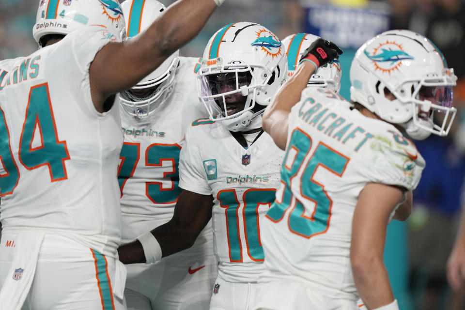 Miami Dolphins wide receiver Tyreek Hill (10) is congratulated by his teammates after scoring a touchdown during the first half of an NFL football game against the Buffalo Bills, Sunday, Jan. 7, 2024, in Miami Gardens, Fla. (AP Photo/Wilfredo Lee)