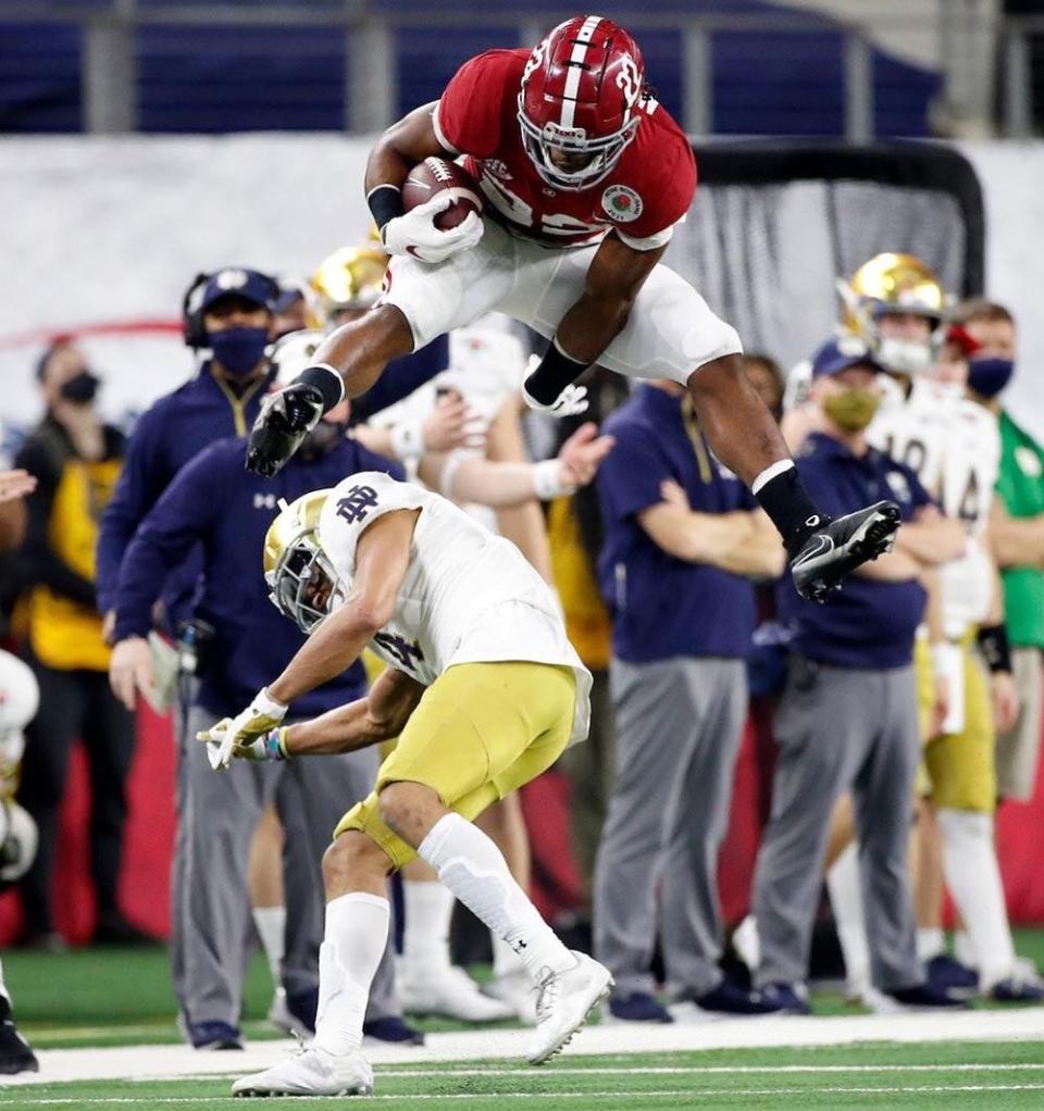 Alabama running back Najee Harris (22) leaps over Notre Dame cornerback Nick McCloud (4) as he makes a long run Jan. 1, 2021, in the College Football Playoff semifinal hosted by the Rose Bowl in AT&T Stadium.