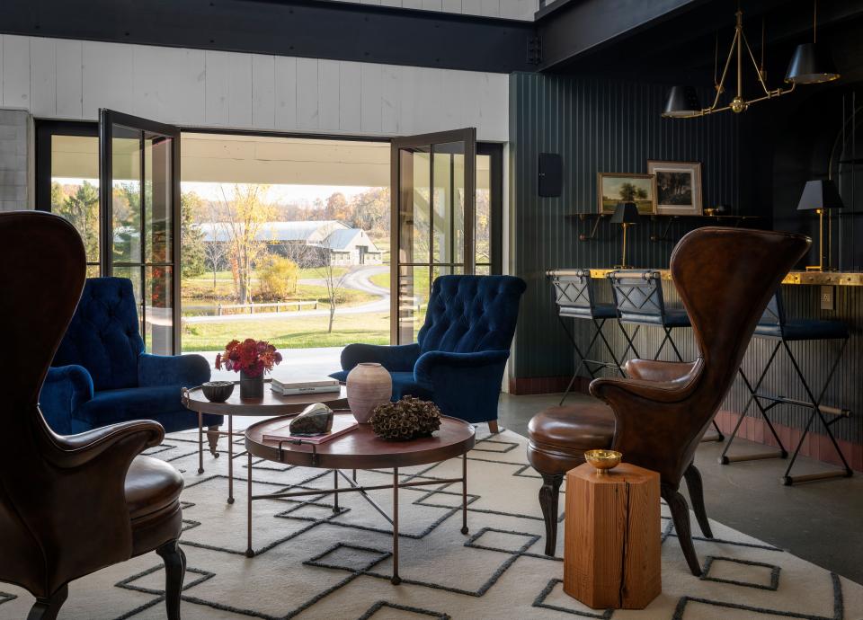 This parlor—and the adjoining bar, seen in the background—has a more urban style than the rest of the house. Richard Felix-Ashman furnished it with Henningsen-style leather wingback chairs (Frits Henningsen was a relatively obscure Danish designer who began producing furniture in the early 1900s), tufted library chairs upholstered in blue velvet, and iron-and-leather tables from Casamidy.