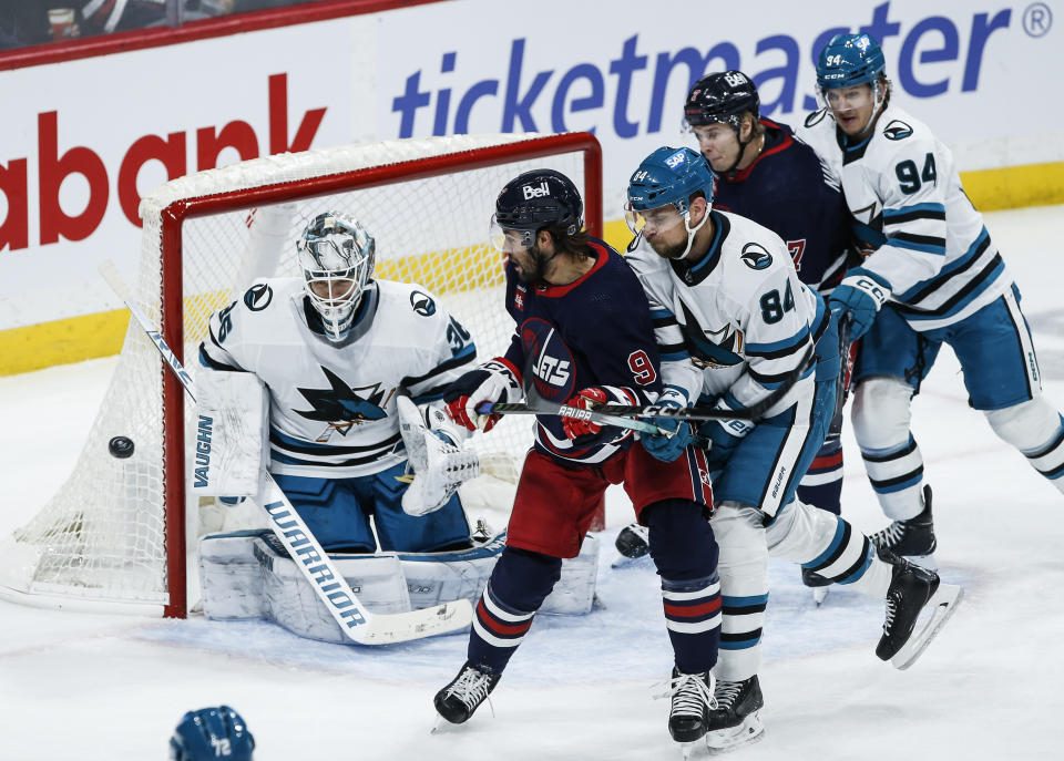 San Jose Sharks goaltender Kaapo Kahkonen (36) makes a save as Jan Rutta (84) defends against Winnipeg Jets' Alex Iafallo (9) during the first period of an NHL hockey game Wednesday, Feb. 14, 2024, in Winnipeg, Manitoba. (John Woods/The Canadian Press via AP)