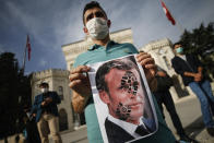 A youth holds a photograph of France's President Emmanuel Macron, stamped with a shoe mark, during a protest against France in Istanbul, Sunday, Oct. 25, 2020. Turkish President Recep Tayyip Erdogan on Sunday challenged the United States to impose sanctions against his country while also launching a second attack on French President Emmanuel Macron. Speaking a day after he suggested Macron needed mental health treatment because of his attitude to Islam and Muslims, which prompted France to recall its ambassador to Ankara, Erdogan took aim at foreign critics. (AP Photo/Emrah Gurel)