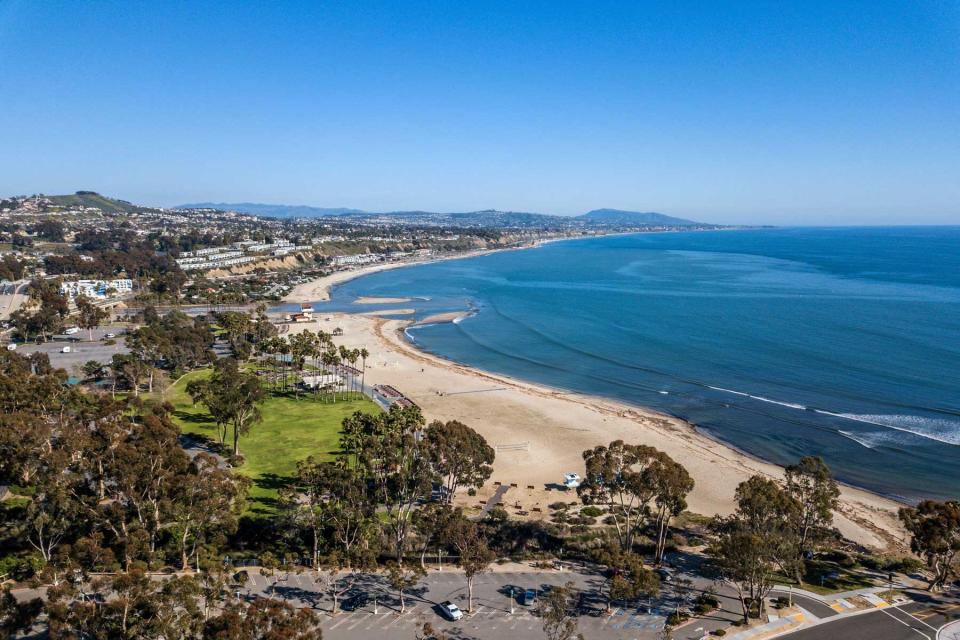 An aerial view of Doheny State Beach and the coastline running through Capistrano Beach to San Clement. Bright sunny day with an empty beach and mild surf.