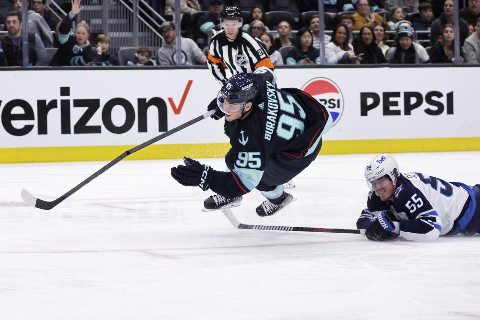 Seattle Kraken left wing Andre Burakovsky (95) goes down with Winnipeg Jets center Mark Scheifele (55) called for tripping during the third period of an NHL hockey game, Friday, March 8, 2024, in Seattle. The Jets won 3-0. (AP Photo/John Froschauer)