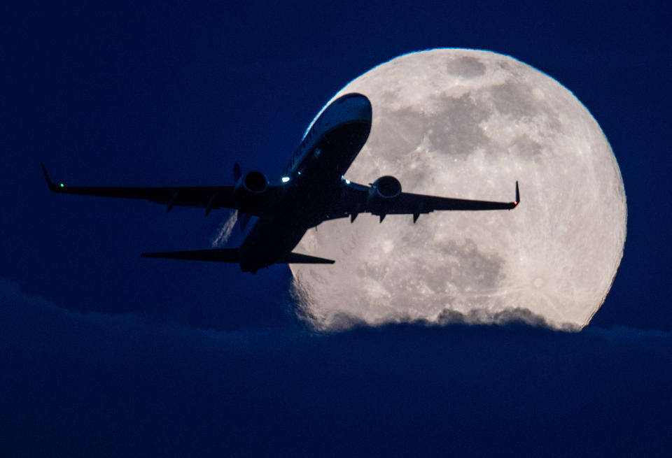 Hessen, Frankfurt/Main: Eine Passagiermaschine startet auf dem Flughafen Frankfurt vor dem tief am Himmel stehenden "Supermond". (Bild: Boris Roessler/dpa)