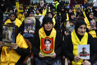 Hezbollah supporters hold pictures of their relatives who died fighting with Hezbollah as they listen to a speech of Hezbollah leader Sayyed Hassan Nasrallah via a video link, during a ceremony marking the "Hezbollah Martyr Day," in the southern Beirut suburb of Dahiyeh, Lebanon, Saturday, Nov. 11, 2023. (AP Photo/Hassan Ammar)