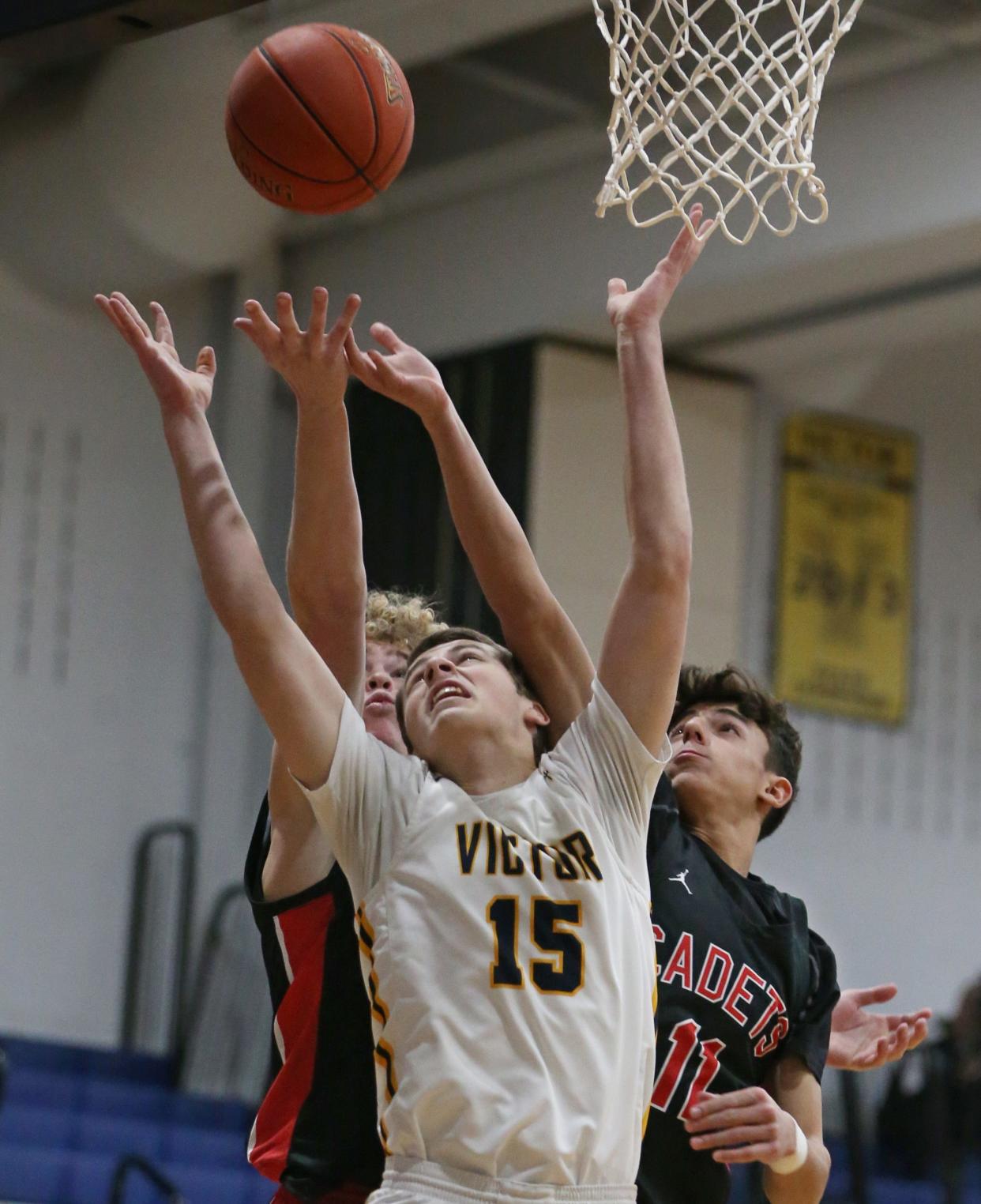 Victor's Garrett Clar battles for a rebound against Hilton's Benjamin Sneddon and Brady Gerig.