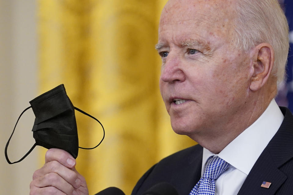 President Joe Biden holds up his face mask as he speaks about vaccine requirements for federal workers in the East Room of the White House in Washington, Thursday, July 29, 2021. (AP Photo/Susan Walsh)