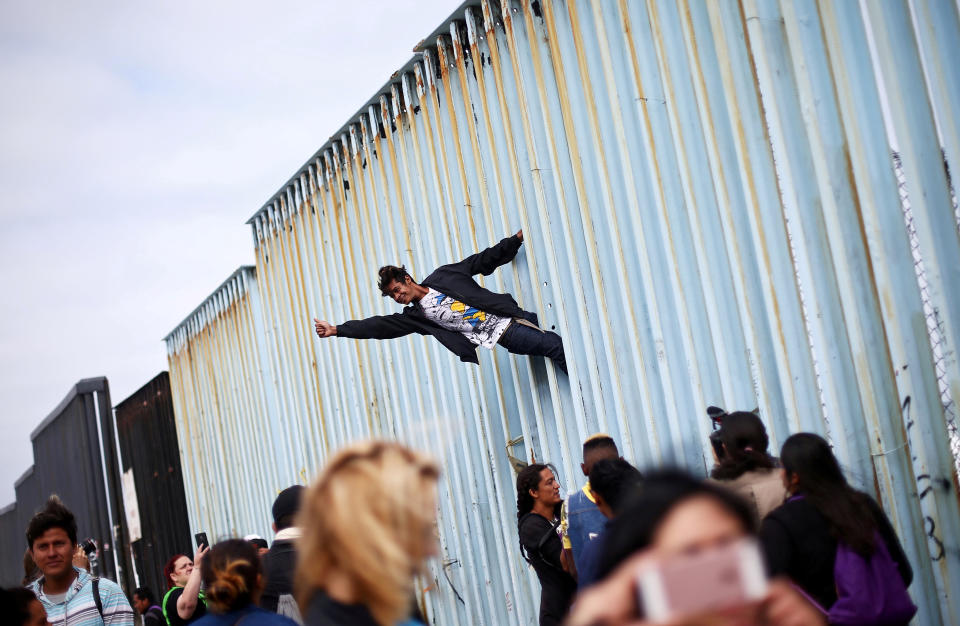 <p>Central American migrants sit on top of the border wall on the beach in San Diego during a gathering of migrants living on both sides of the border, April 29, 2018. (Photo: Chris Carlson/AP) </p>