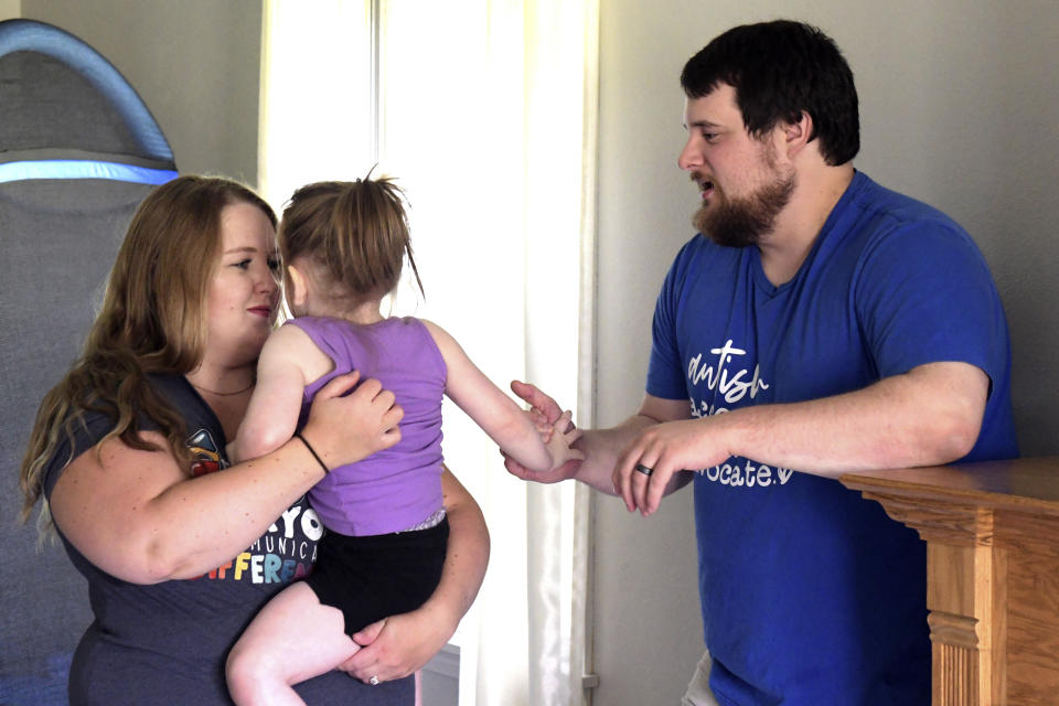 Lindsey and Kendrick Faulkner, hold their 2-year-old daughter, Aria, at their home in Peoria, Ill. during an early intervention therapy session on Aug. 15, 2023. (AP Photo/Ron Johnson)