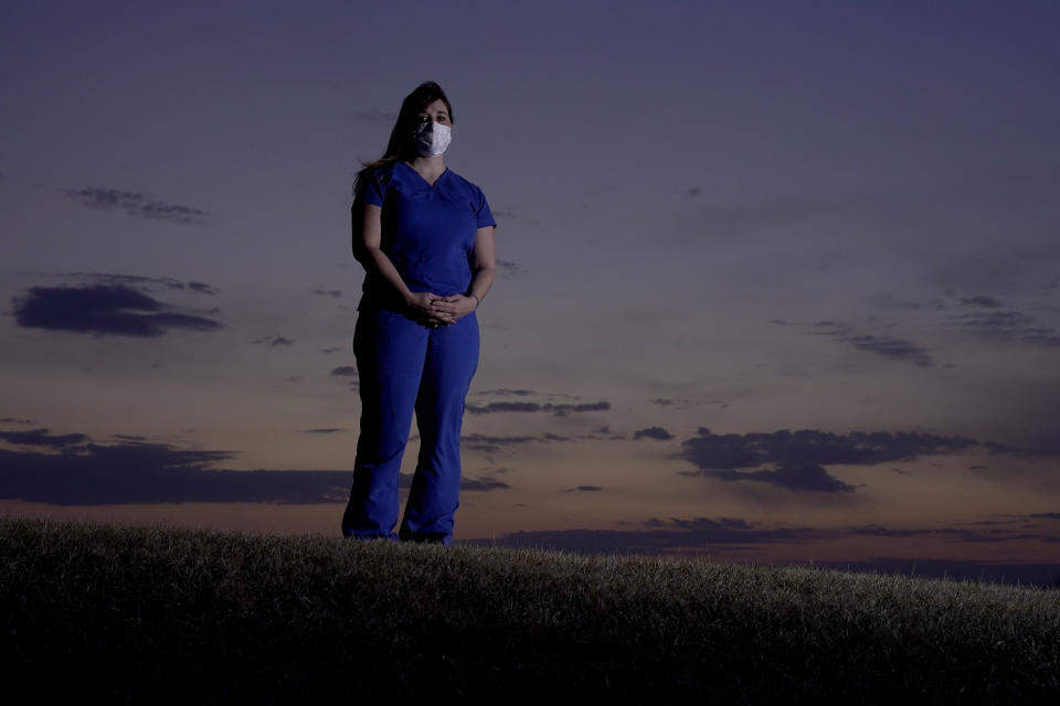 Emergency room nurse L'Erin Ogle stands at dawn before starting her 12-hour shift at a nearby hospital Tuesday, March 9, 2021, in Overland Park, Kan. After a year of working long hours taking care of COVID-19 patients, Ogle feels obligated to speak out when she sees misinformation related to the pandemic in her community. (AP Photo/Charlie Riedel)