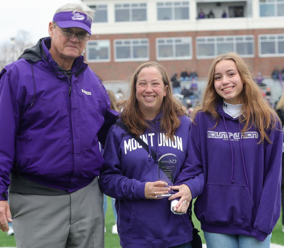 Former Mount Union football coach and athletic director Larry Kehres, left, presented a posthumous Lifetime Achievement Award from the College Sports Communicators group to honor the late Lenny Reich to his wife, Helen, center, and daughter Caroline before the start of Saturday's football game against Baldwin Wallace at Kehres Stadium. Reich, a former Mount Union sports information director, died in October 2022 after serving more than 25 years in his roles at Mount Union and Alliance City Schools.