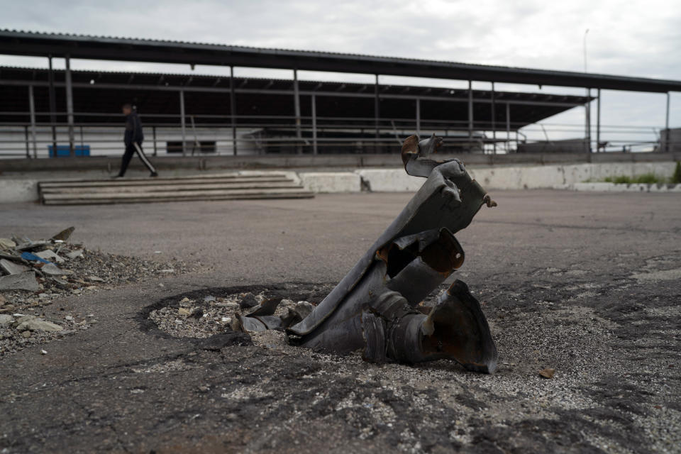 An employee walks past part of a rocket that sits wedged in the ground in an area at the Veres farm in Novomykolaivka, eastern Ukraine, Saturday, Sept. 10, 2022. All work has halted on this large eastern Ukrainian farm, whose fields and compound have been hit so many times by mortars, rockets, missiles and cluster bombs that its workers are unable to sow the crater-scarred land or harvest any crops. (AP Photo/Leo Correa)