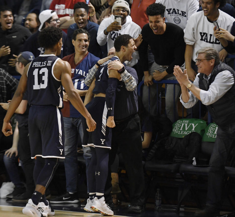 Yale's Alex Copeland, center, celebrates with fans as teammate Trey Phills, left, looks on in the final minute of an NCAA college basketball game for the Ivy League championship against Harvard at Yale University in New Haven, Conn., Sunday, March 17, 2019, in New Haven, Conn. (AP Photo/Jessica Hill)