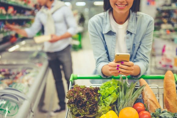 A woman using her smartphone while grocery shopping