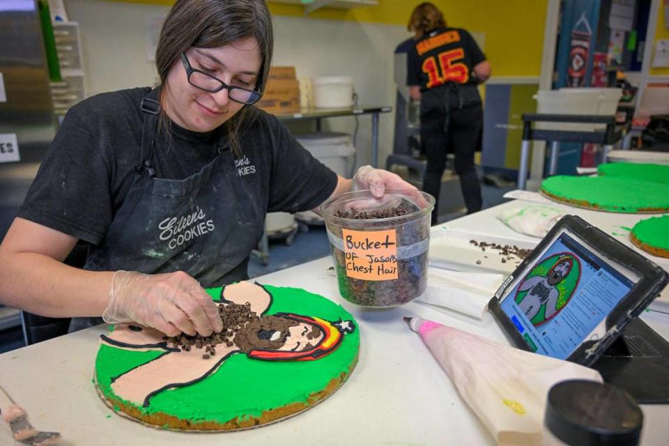 Hannah Stumpner, manager of Eileen’s Colossal Cookies in Liberty, adds a bit of “chest hair’ to a cookie cake she was making Thursday at the bakery. The chest hair is created from chocolate curls. 