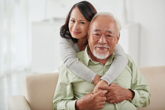 An elderly couple embracing one another.