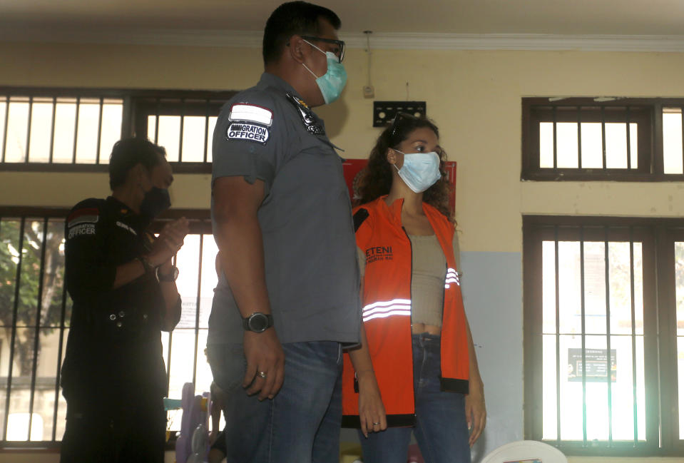 Heather Mack of Chicago, Ill., right, is escorted by Indonesian immigration officers at Immigration detention center in Jimbaran, Bali, Indonesia on Friday, Oct. 29, 2021. The American woman convicted of helping to kill her mother on Indonesia's tourist island of Bali in 2014 walked free from prison Friday after serving seven years of a 10-year sentence and will be deported to the United States. (AP Photo/Firdia Lisnawati)