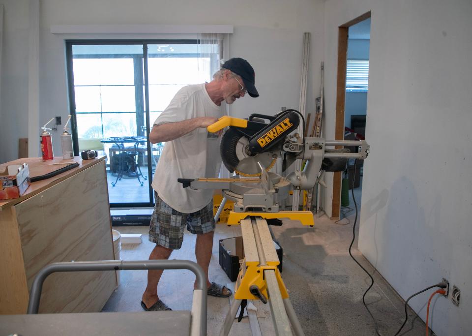 David Bormuth cuts a piece of baseboard trim while working on his condo off Island Park Road in Fort Myers on Thursday, Sept. 21, 2023. He's been doing the work himself after the company hired by his HOA after Hurricane Ian stopped working after only installing the sub-floors. Some other residents also got drywall installed.