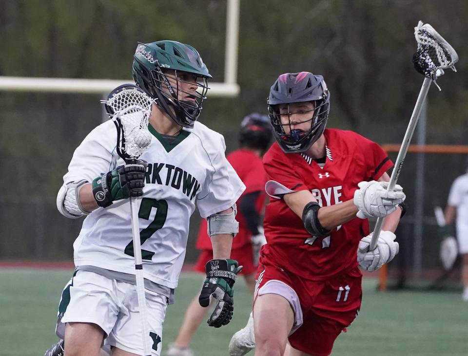 Yorktown's Ryan Vogel (2) works the ball around Rye's Gage Sasse (11) during their 9-8 double overtime win in boys lacrosse at Yorktown High School in Yorktown Heights. Tuesday, April 30, 2024.