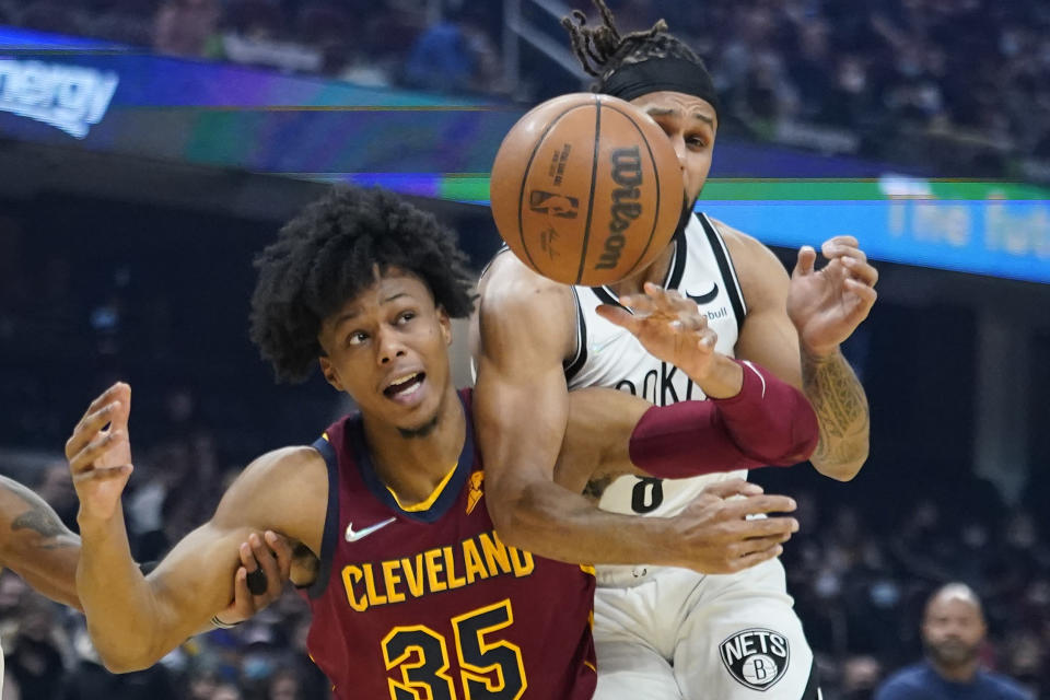 Cleveland Cavaliers' Isaac Okoro (35) and Brooklyn Nets' Patty Mills (8) battle for the ball in the first half of an NBA basketball game, Monday, Jan. 17, 2022, in Cleveland. (AP Photo/Tony Dejak)