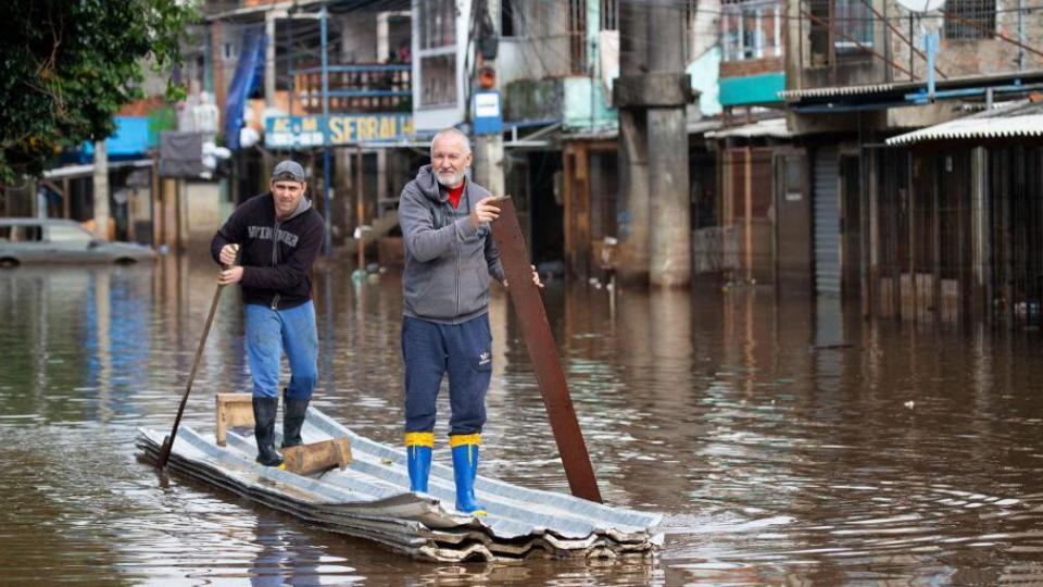 Two men paddle a makeshift canoe down a flooded street in the Vila Farrapos area of Porto Alegre, Brazil, on 29 May 2024