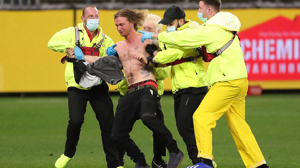 A pitch invader, pictured here being escorted from the field during Geelong's clash with Collingwood.