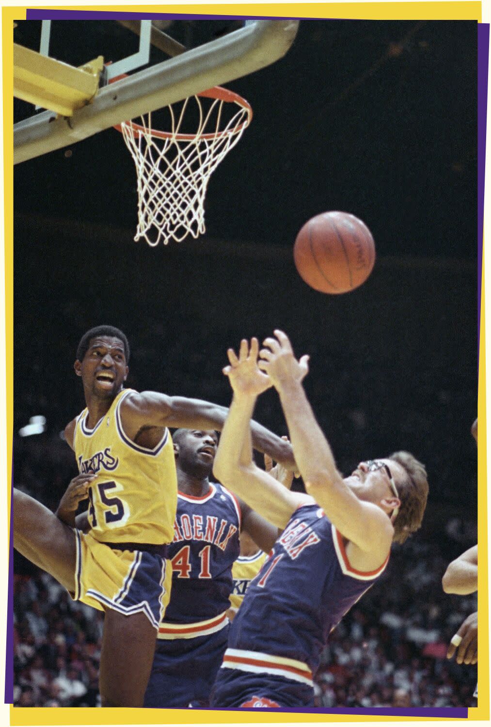 Photo of basketball players jumping up and fighting for a loose ball under a basket.