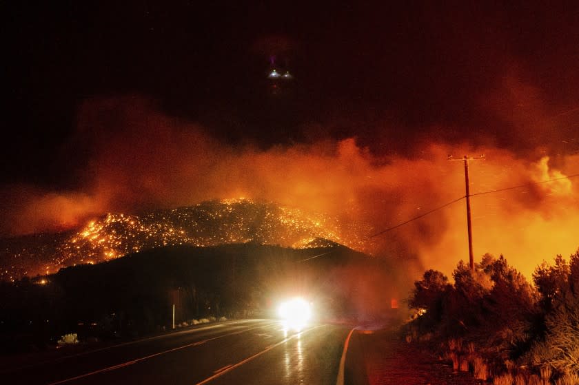 A car makes its way along Highway 395 in Mono County as the Mountain View fire burns in the background.