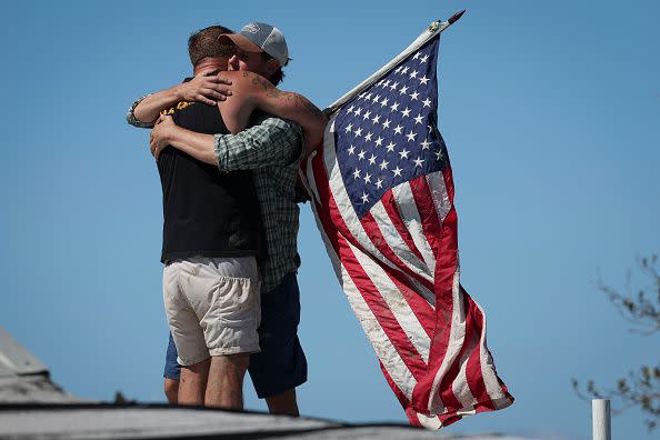 MATLACHA, FLORIDA - SEPTEMBER 30: Whitney Hall (R) embraces a friend atop the remains of his home amidst wreckage left in the wake of Hurricane Ian on the island of Matlacha on September 30, 2022 in Matlacha, Florida. The hurricane brought high winds, storm surge and rain to the area causing severe damage. (Photo by Win McNamee/Getty Images)