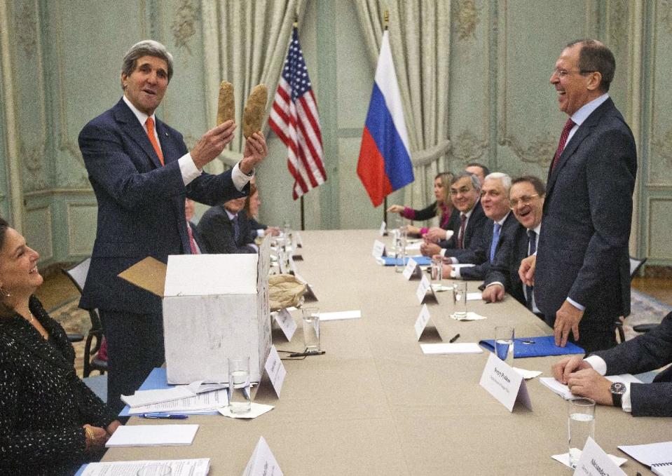 U.S. Secretary of State John Kerry holds up a pair of Idaho potatoes as a gift for Russia's Foreign Minister Sergey Lavrov, standing right, at the start of their meeting at the U.S. Ambassador's residence in Paris, France, Monday, Jan. 13, 2014. Kerry is in Paris on a two-day meeting on Syria to rally international support for ending the three-year civil war in Syria. For some watchers of international diplomacy, the somber road to Syrian peace was overrun Monday by potatoes and furry pink hats. (AP Photo/Pablo Martinez Monsivais, Pool)