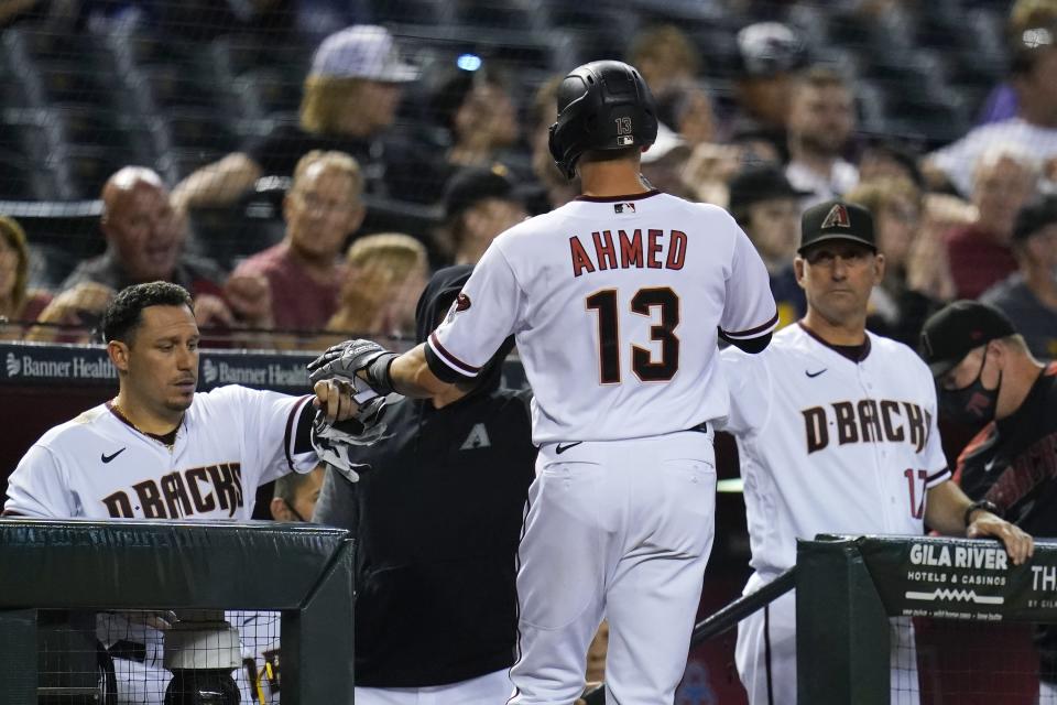 Arizona Diamondbacks' Nick Ahmed (13) celebrates his run scored against the Milwaukee Brewers with teammate Asdrubal Cabrera, left, and manager Torey Lovullo, right, during the second inning of a baseball game Monday, June 21, 2021, in Phoenix. (AP Photo/Ross D. Franklin)