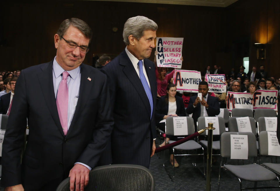 Protesters from Code Pink hold up signs as Secretary of State John Kerry and Defense Secretary Ashton Carter arrive to testify before the Senate Foreign Relations Committee on Capitol Hill on March 11, 2015. 