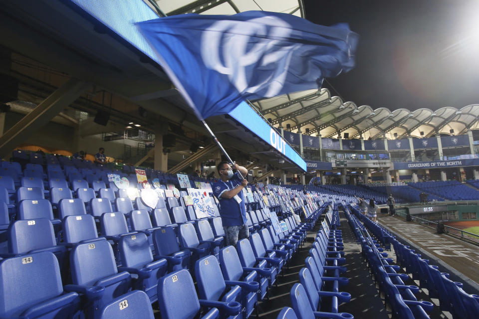 A lone cheerleader waves a flag on the Stadium stands with no audience at Xinzhuang Baseball Stadium in New Taipei City, Taiwan, Friday, April 24, 2020. Taiwan's five-team Chinese Professional Baseball League is barring spectators over concerns they would spread the deadly coronavirus, meaning games are played with plastic seats void of fans. (AP Photo/Chiang Ying-ying)